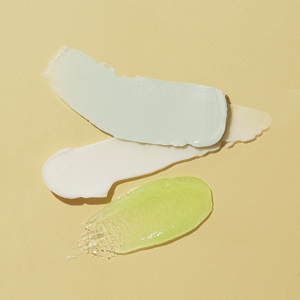 Nahaufnahme von weißer Creme und grünem Gel als Produkttextur einer Hautpflege auf goldenem Hintergrund