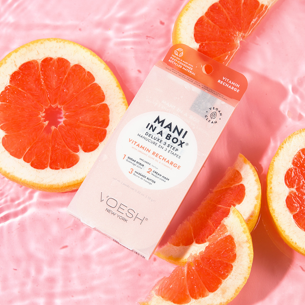 LOVESH Mani in a Box Vitamin Recharge Deluxe 3-Step Maniküre-Packung, inszeniert mit frischen Grapefruits auf rosa Hintergrund