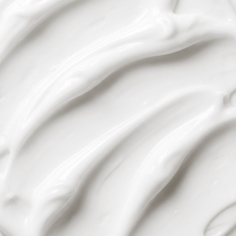 Weiße, cremige Kosmetik- oder Pflegeprodukt-Textur in Nahaufnahme mit glänzender, sanft gewellter Oberfläche