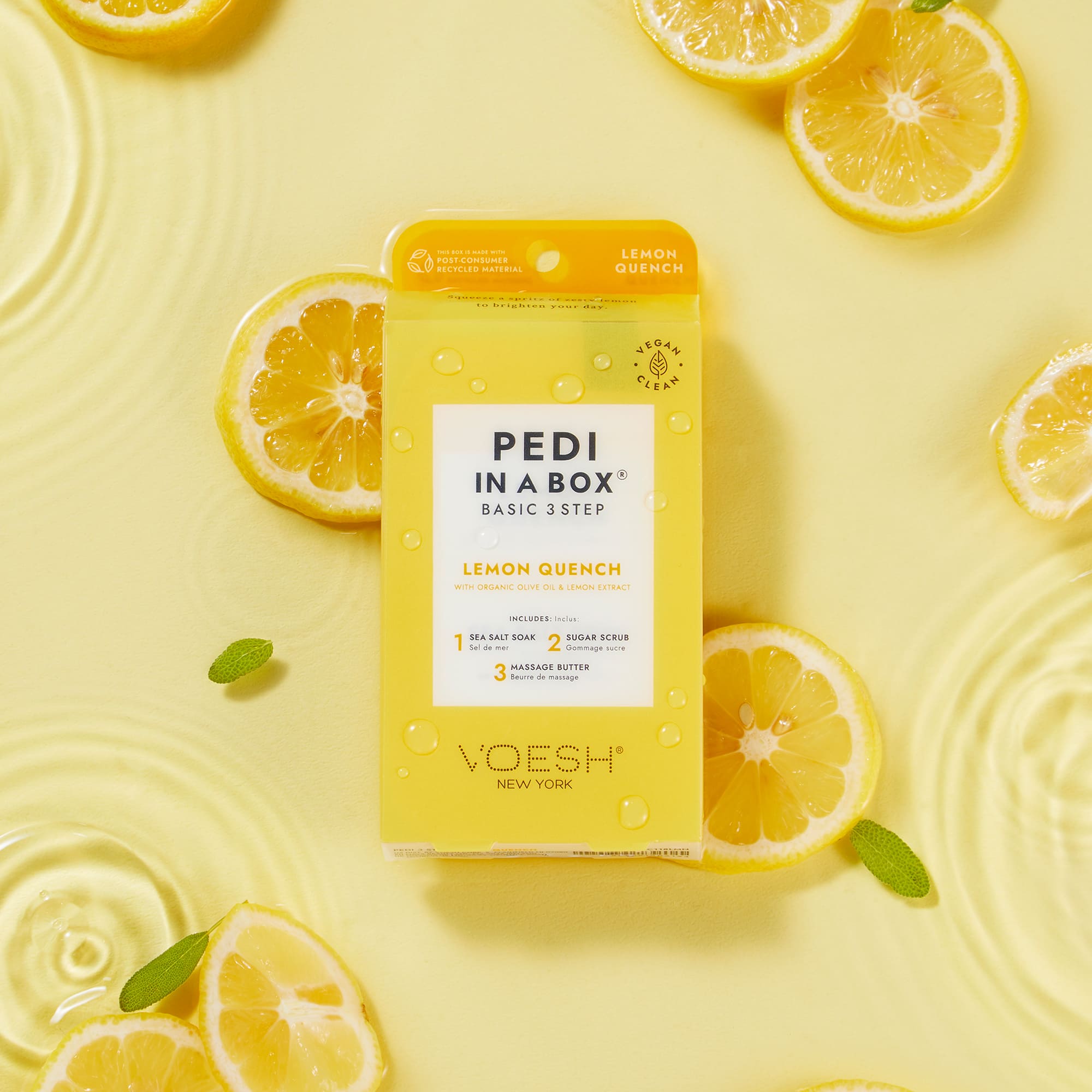 Voesh Pedi in a Box Basic 3 Step Lemon Quench, vegane 3-Schritt-Spa-Pediküre mit Zitronenextrakt, Meersalzbad, Zuckerpeeling und Massage Butter, inszeniert mit frischen Zitronenscheiben auf gelbem Hintergrund