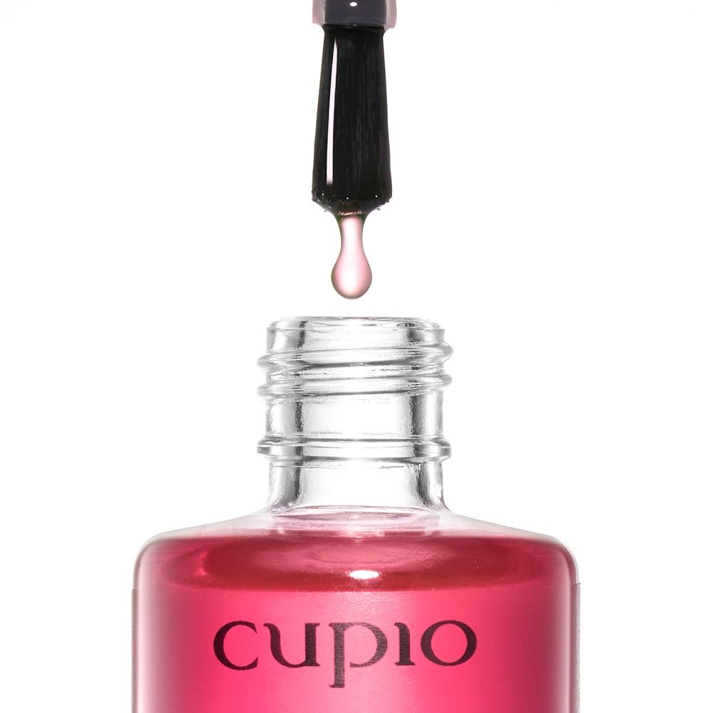 Geöffnete Flasche mit Pinsel und Tropfen der Cupio Drops Of Care Nagelkur 15 ml, transparente glänzende Pflege zur Stärkung weicher, brüchiger und geschädigter Nägel