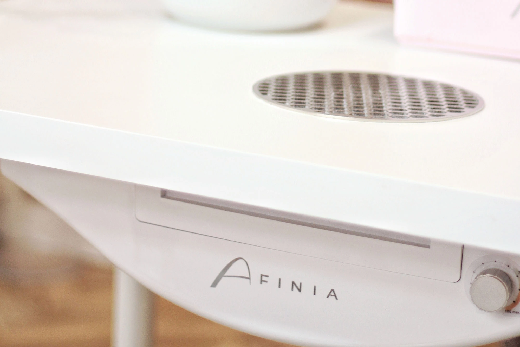 Detailansicht eines weißen Tischs mit Lüftungsgitter und AFINIA Logo