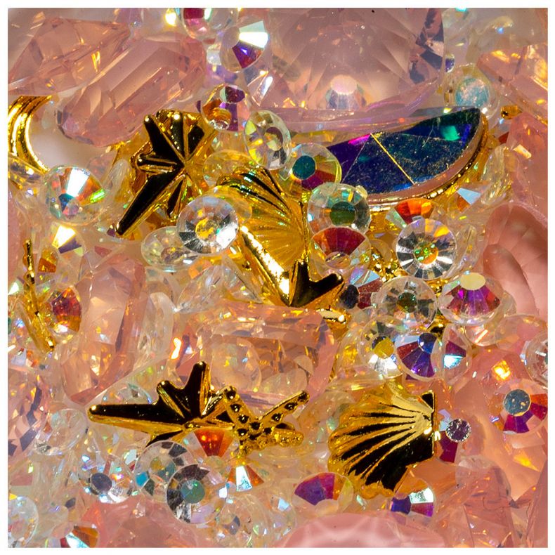 Bunte Glitzersteine und goldene Dekorationselemente auf pinkem Hintergrund
