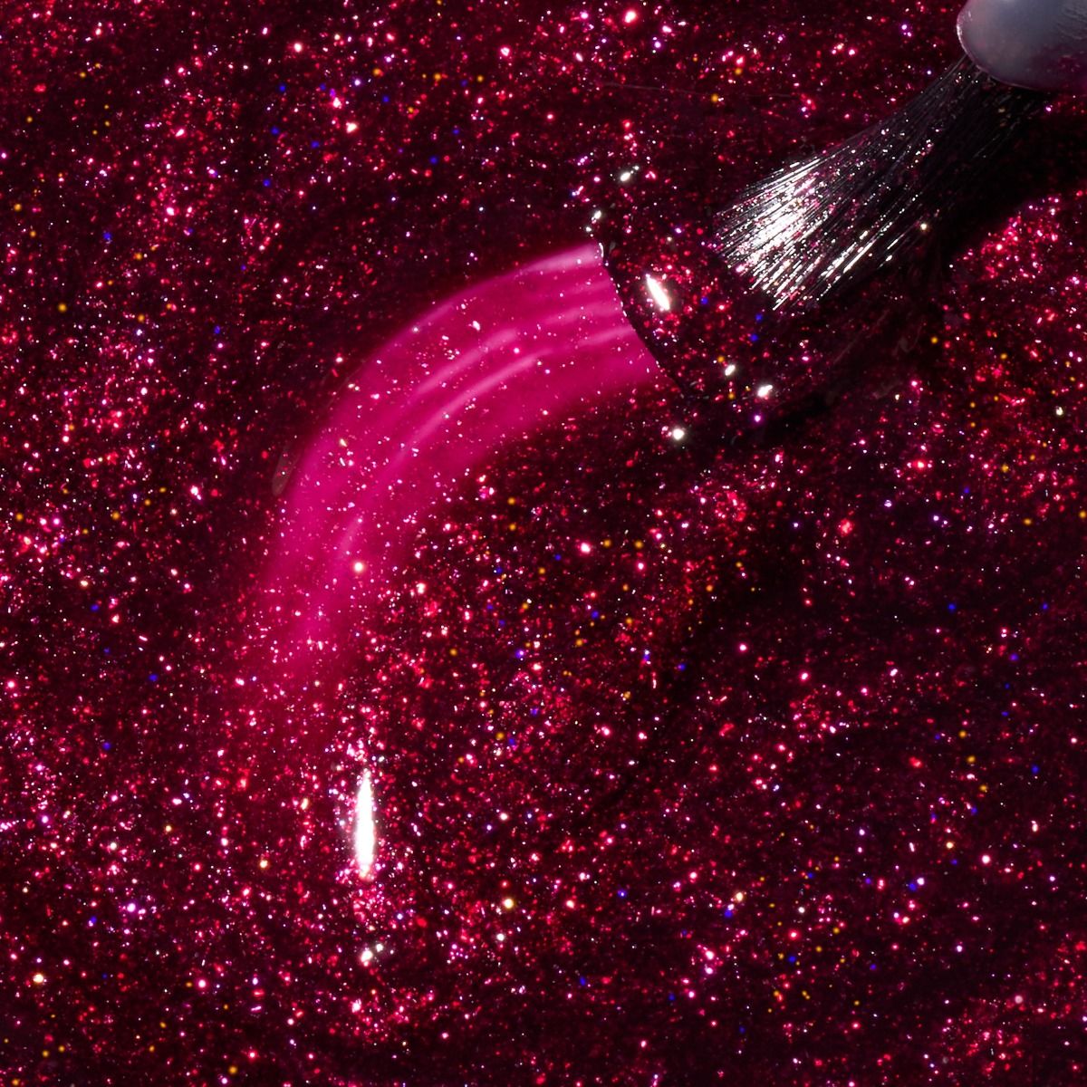 Nahaufnahme eines pinkfarbenen Glitzer-Nagellacks mit Pinsel und Lackspur auf intensiv funkelndem Glitter-Hintergrund