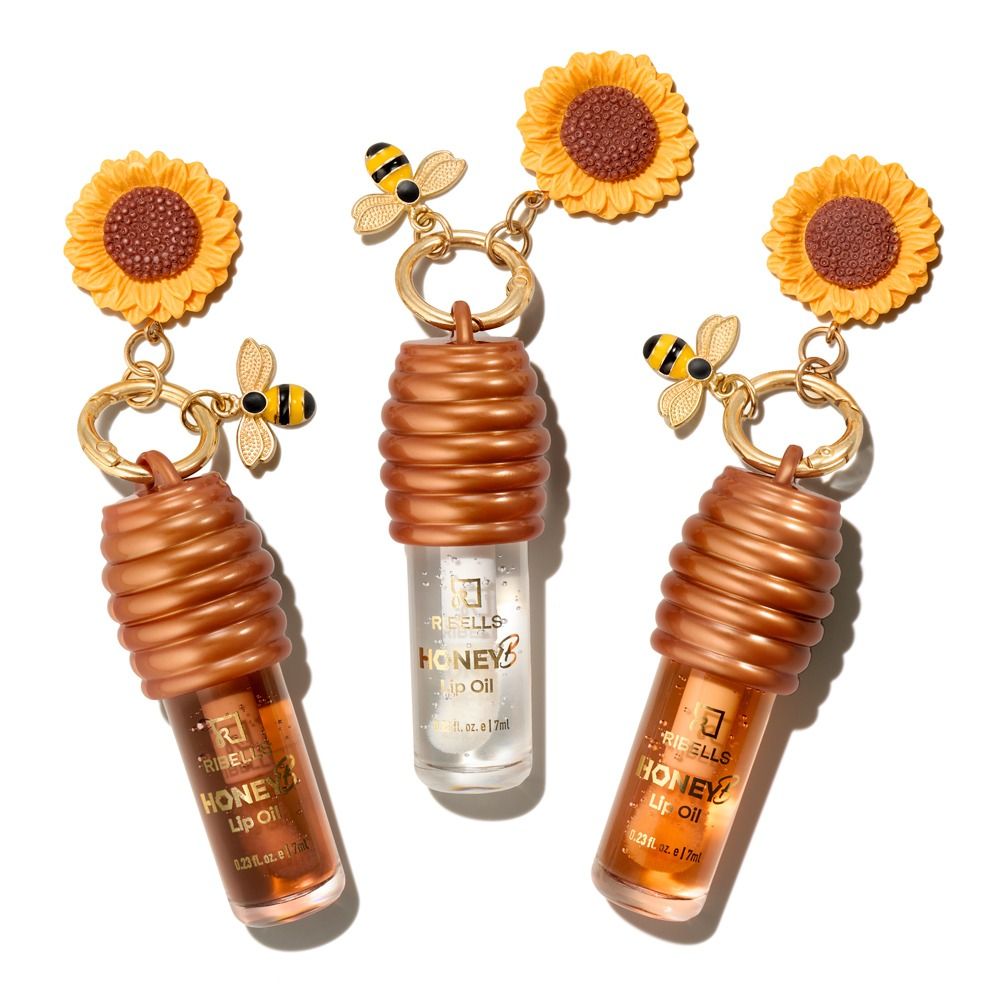 Drei Ribells Honey B Bee Kissed Lippenöle mit Sonnenblumen- und Bienen-Anhängern, inspiriert von Honig, für gepflegte, hydratisierte Lippen mit glänzendem, voller wirkendem Finish.