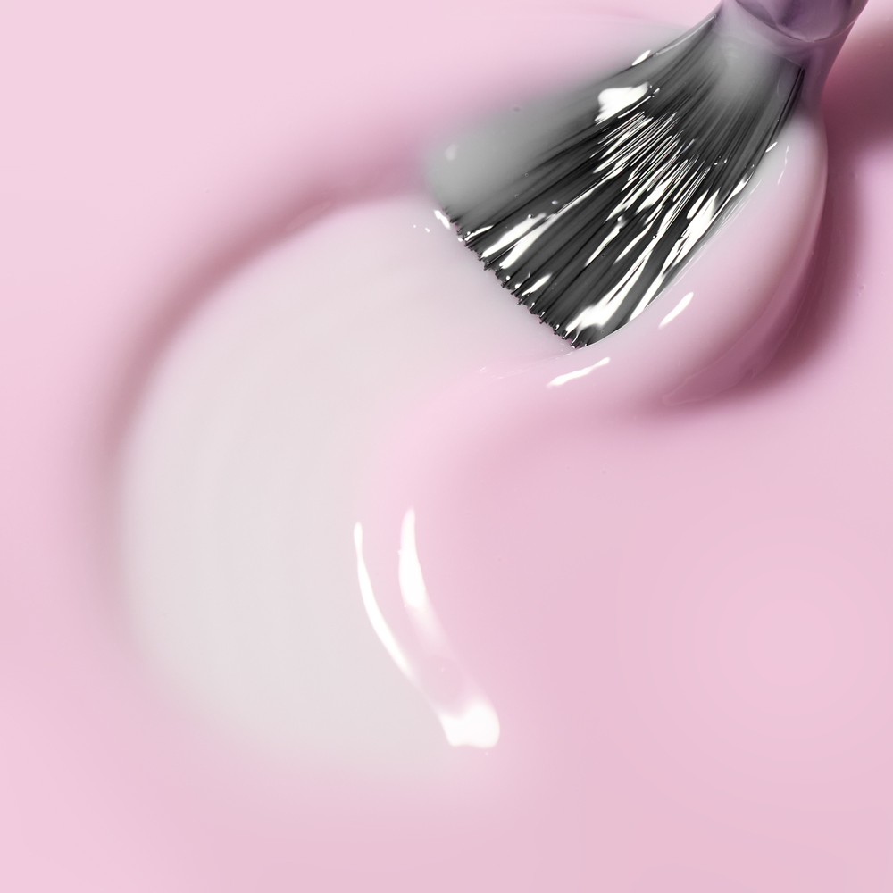 Pinsel trägt die rosa Long Lasting Fiber Base von Cupio auf – modellierbare Base mit synthetischen Fasern für starke Haftung, flexible Stabilität und natürliche Maniküren