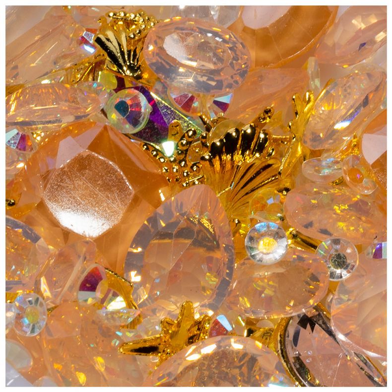 Detailaufnahme von funkelnden Dekosteinen und goldenen Schmuckelementen auf einem hellen Hintergrund