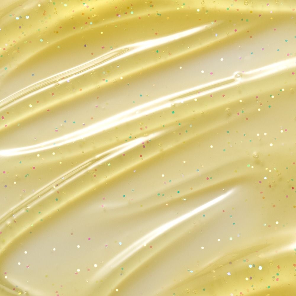 Nahaufnahme einer gelben, glitzernden Gel-Textur mit bunten Partikeln