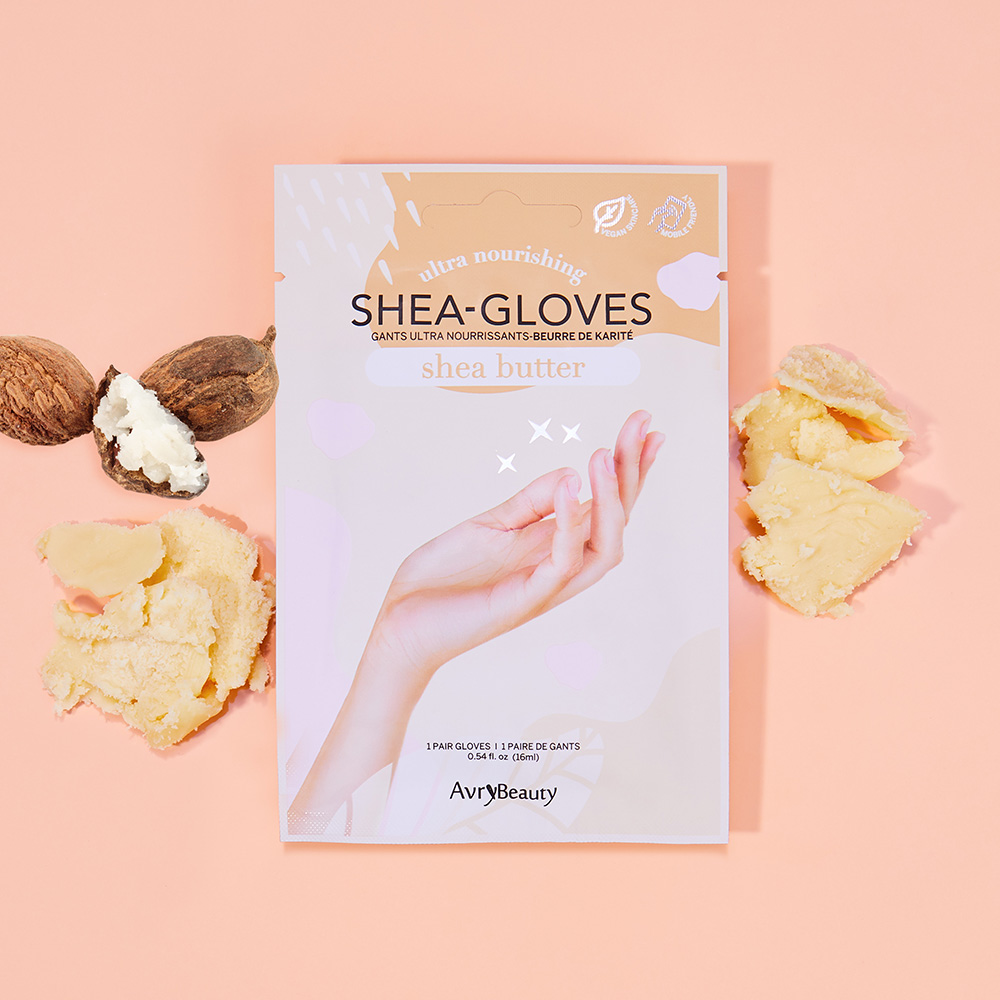 AvryBeauty Shea-Gloves Handmaske mit Sheabutter in der Verpackung, umgeben von Shea-Nüssen und Sheabutter auf rosafarbenem Hintergrund