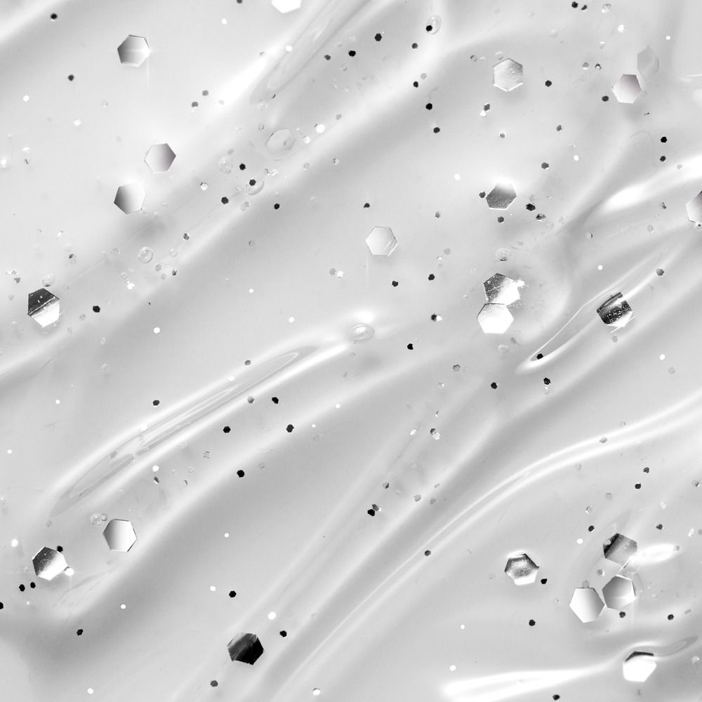 Nahaufnahme einer glitzernden, weißen Textur mit silbernen und schwarzen Partikeln