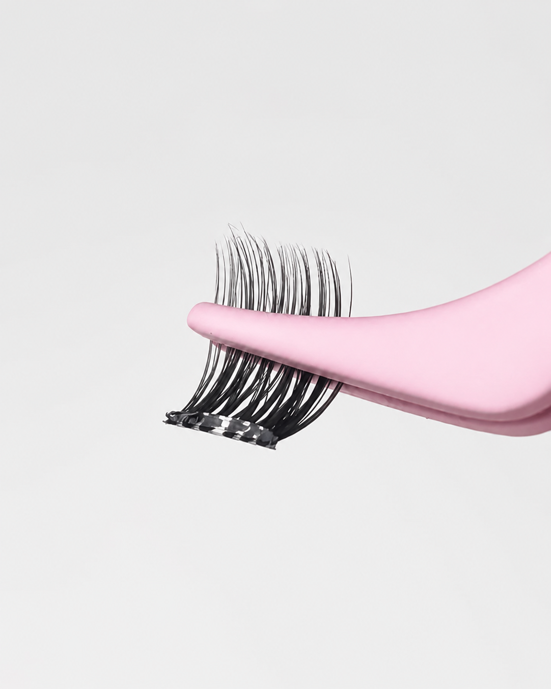 Nahaufnahme eines rosa Applikators, der magnetische künstliche Wimpern für das präzise Aufsetzen hält