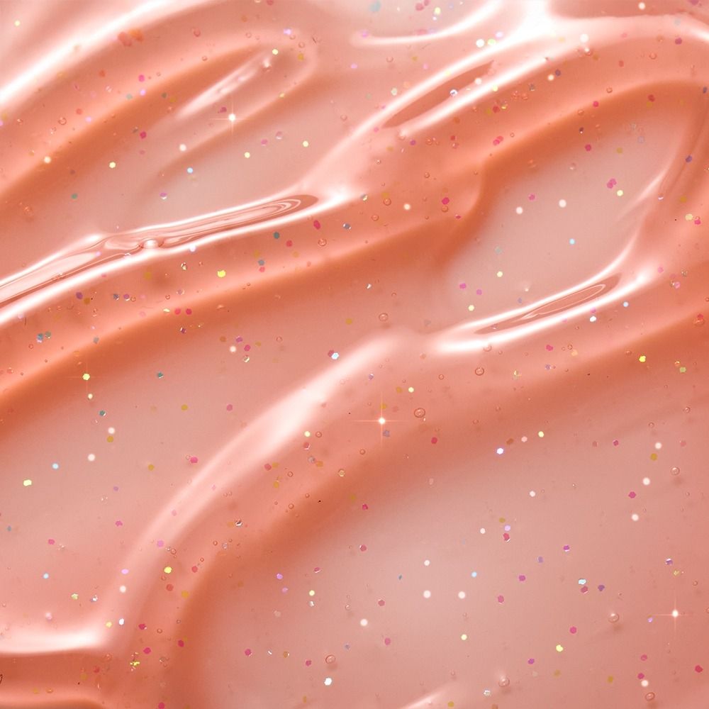Nahaufnahme einer glitzernden, peachfarbenen Creme mit funkelnden, multicolor Partikeln