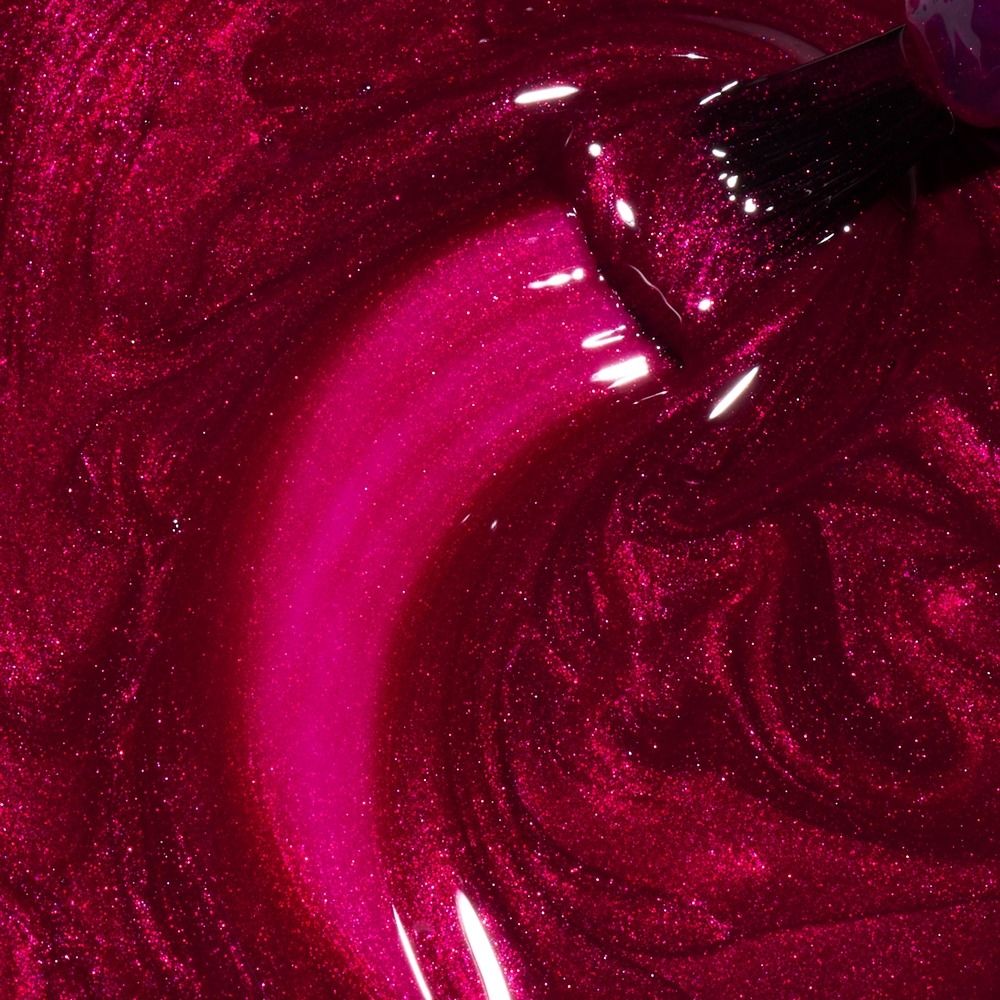 Makroaufnahme von pinkem, schimmerndem Glitzer-Nagellack mit Pinsel beim Auftragen