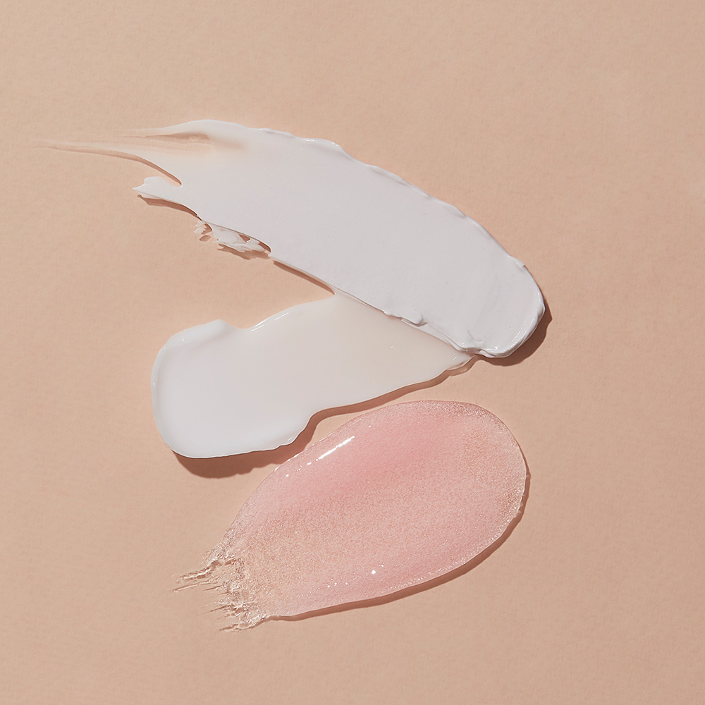 Drei Kosmetik-Texturen auf beigem Hintergrund: weiße Creme, milchige Lotion und rosafarbenes Gel als Produktdarstellung für Hautpflege