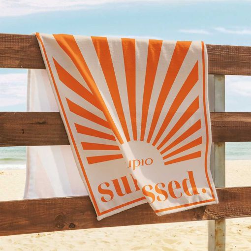Strandhandtuch mit oranges Sonnenmotiv an einem Holzgeländer