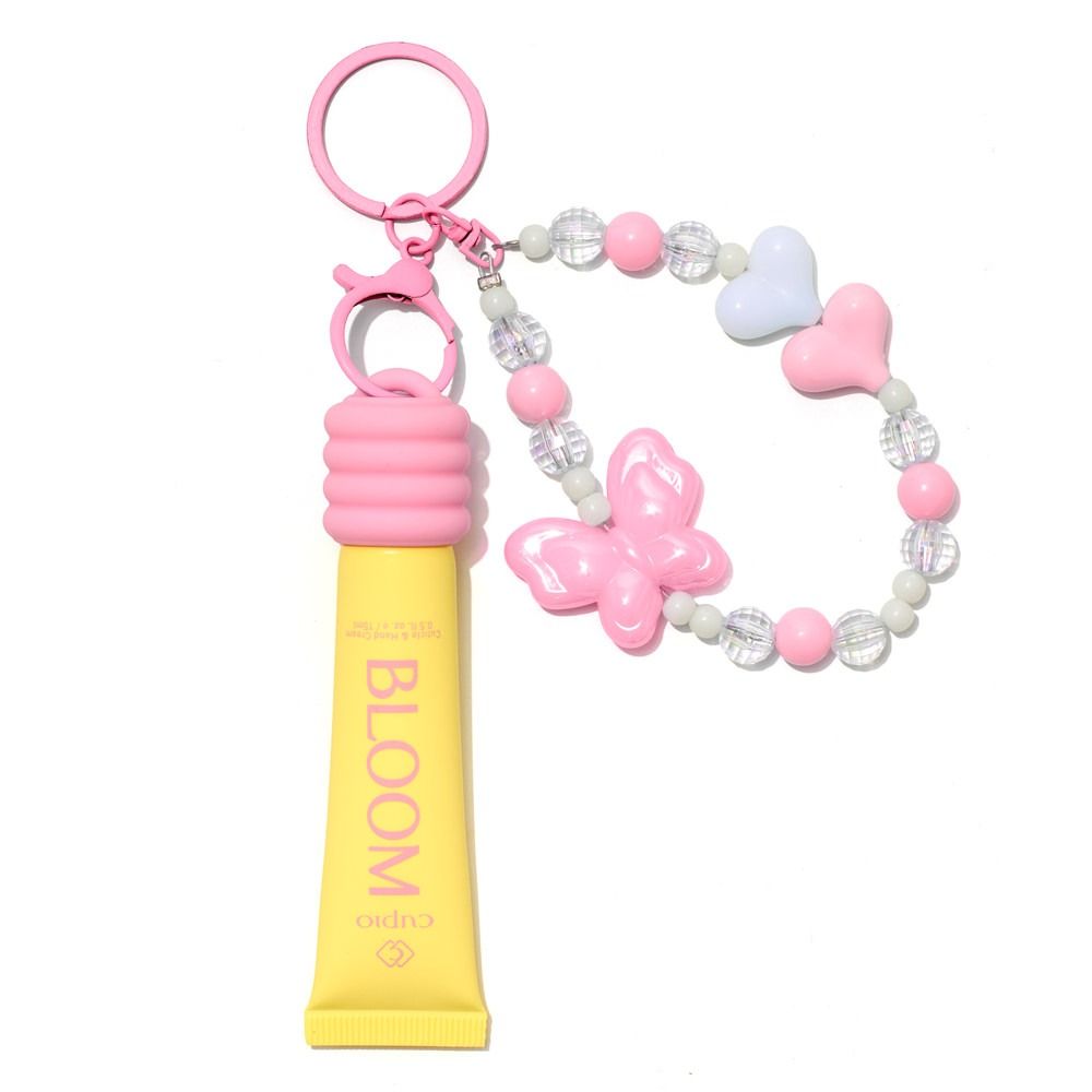 Gelber BLOOM Lipgloss mit rosa Schlüsselring und dekorativem Perlenarmband mit Schmetterling und Herzanhängern