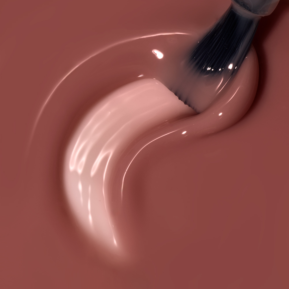 Makroaufnahme eines Pinsels, der cremigen roséfarbenen Nagellack in geschwungener Spur aufträgt