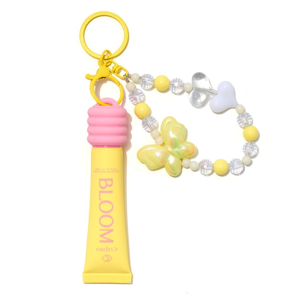 Gelber BLOOM Lipgloss als Schlüsselanhänger mit pinker Kappe, goldfarbenem Ring und Perlenband mit Schmetterling- und Herzanhängern