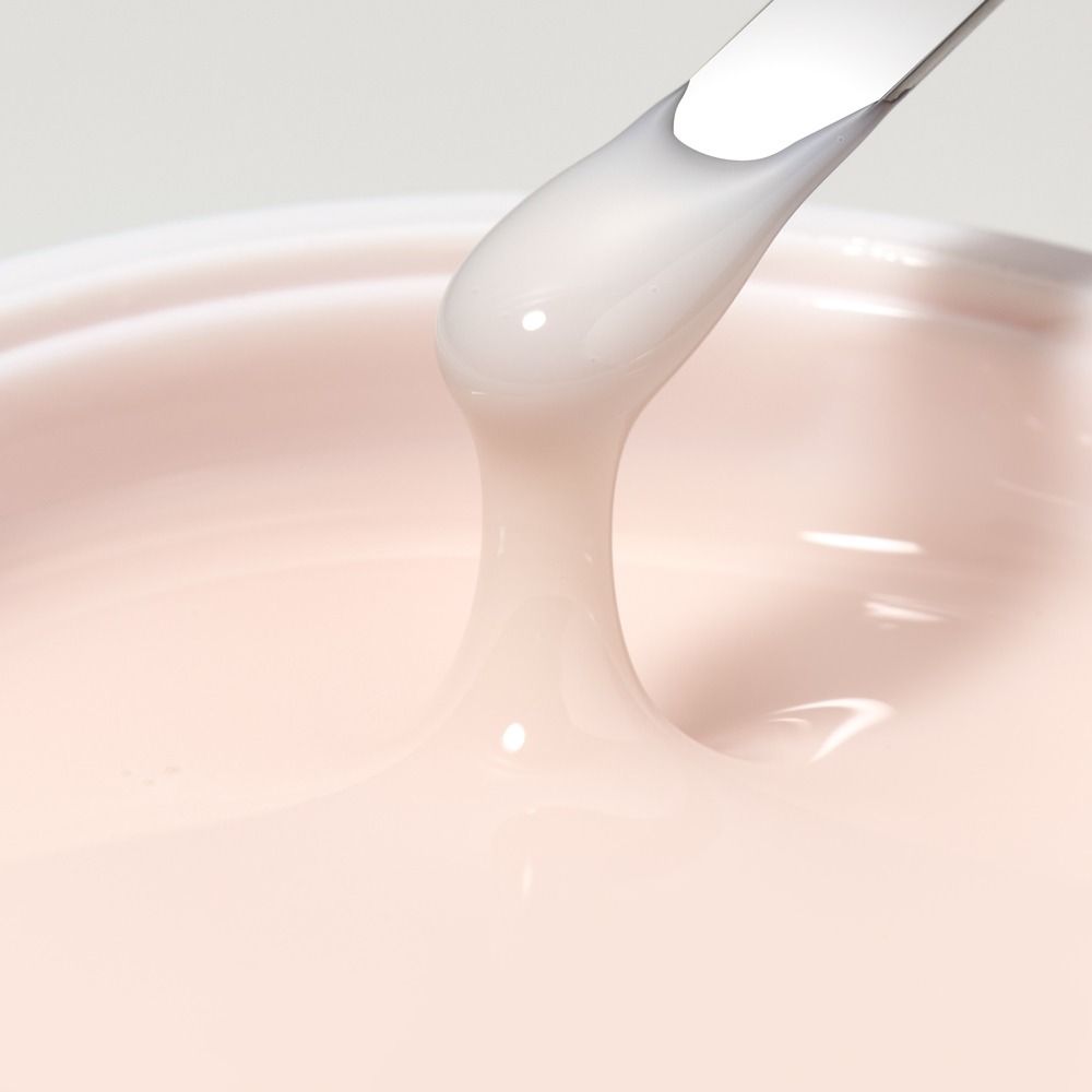 Nahaufnahme einer cremigen rosa Gel- oder Creme-Textur im Tiegel, aufgenommen mit Spatel – Detail eines Kosmetikprodukts