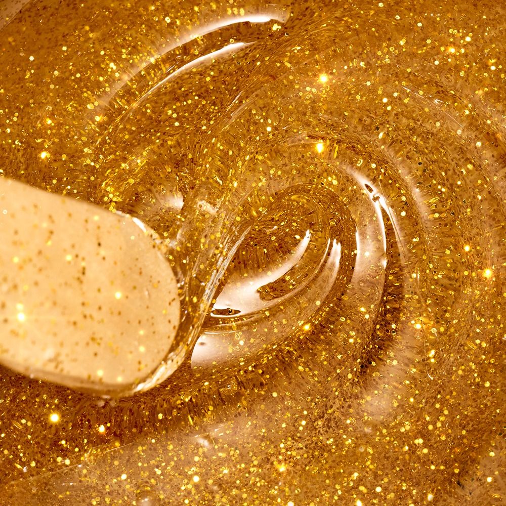 Makroaufnahme eines goldenen Glitzer-Nagellacks mit Pinsel im Fläschchen – funkelnde, zähflüssige Textur